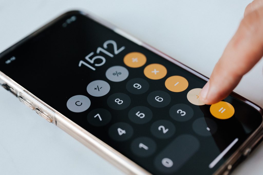 Gemeinkostenzuschlagsatz, Handy mit Taschenrechner App, Finger drückt auf Plus.